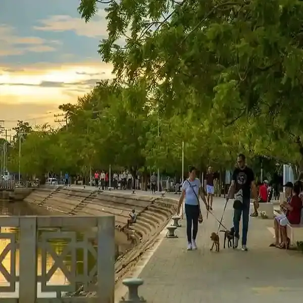 Paseo peatonal en Lorica, Córdoba, con personas disfrutando del atardecer y la naturaleza.