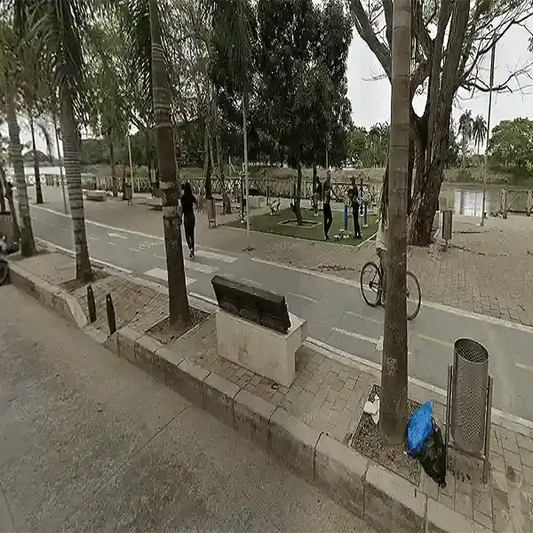 Parque junto al río en Lorica, Córdoba, con árboles, personas y ciclistas disfrutando del espacio pú.