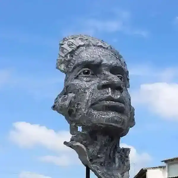 Taga de escultura de un rostro humano en metal en un espacio abierto.