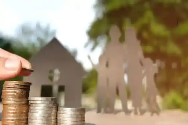 Trámites y servicios 4 Monedas apiladas con fondo de una familia y una casa en un parque.
