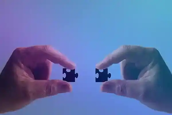 Aliados 1 Manos sosteniendo piezas de rompecabezas en tonos azules y morados.