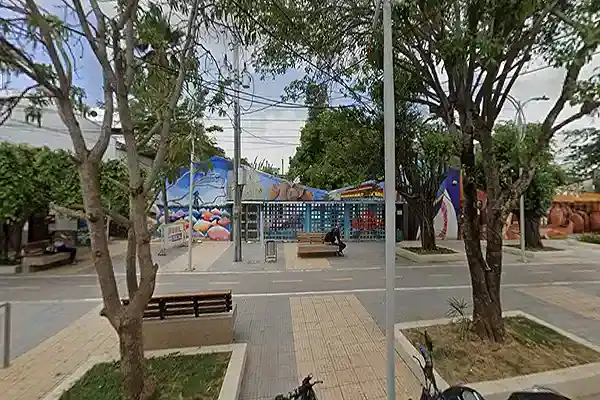 Parque en Lorica con árboles, bancos y área de juegos infantiles.